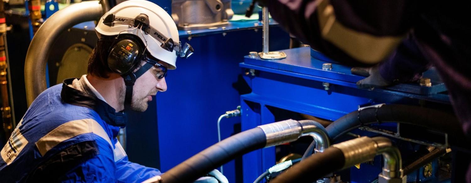 Engineers adjusting machinery wearing PPE