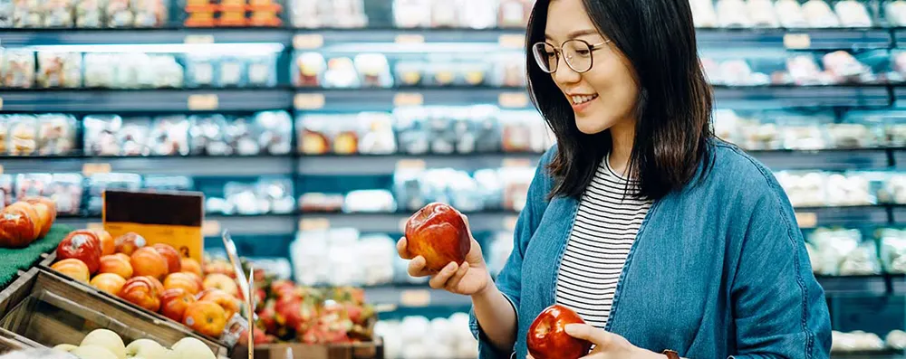 image of a woman choosing apple in supermarket