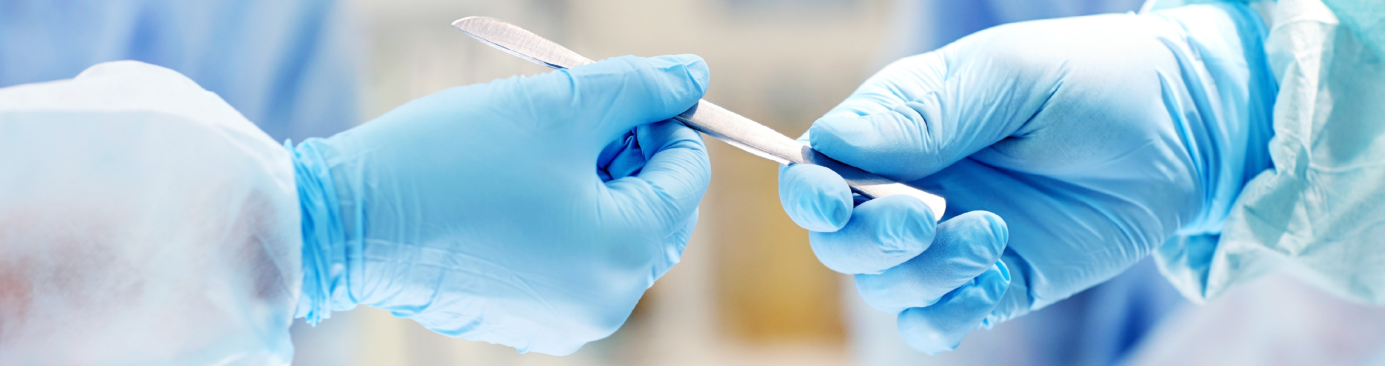 Sterile Processing Image of scalpel being passed during surgery
